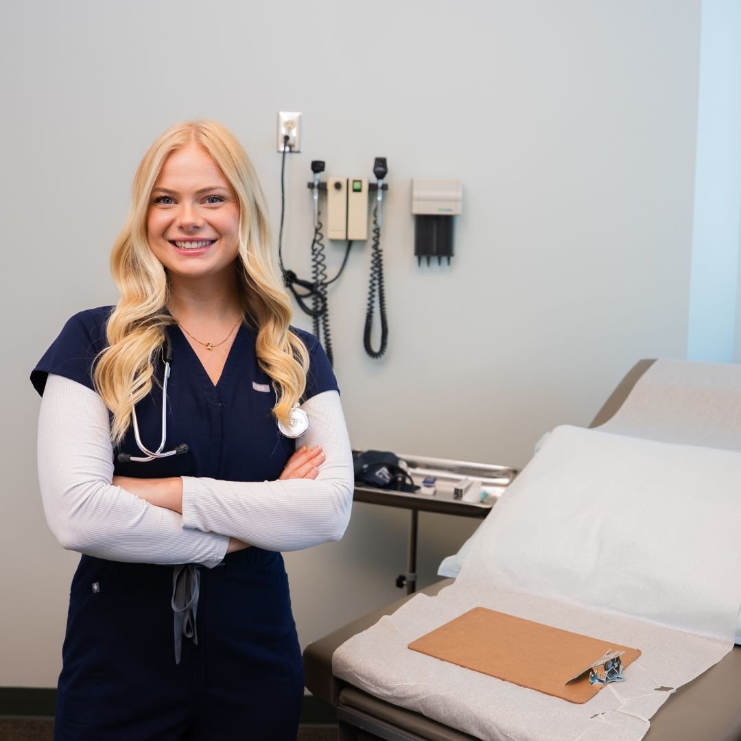 A nurse crossing her arms in a hospital smiling