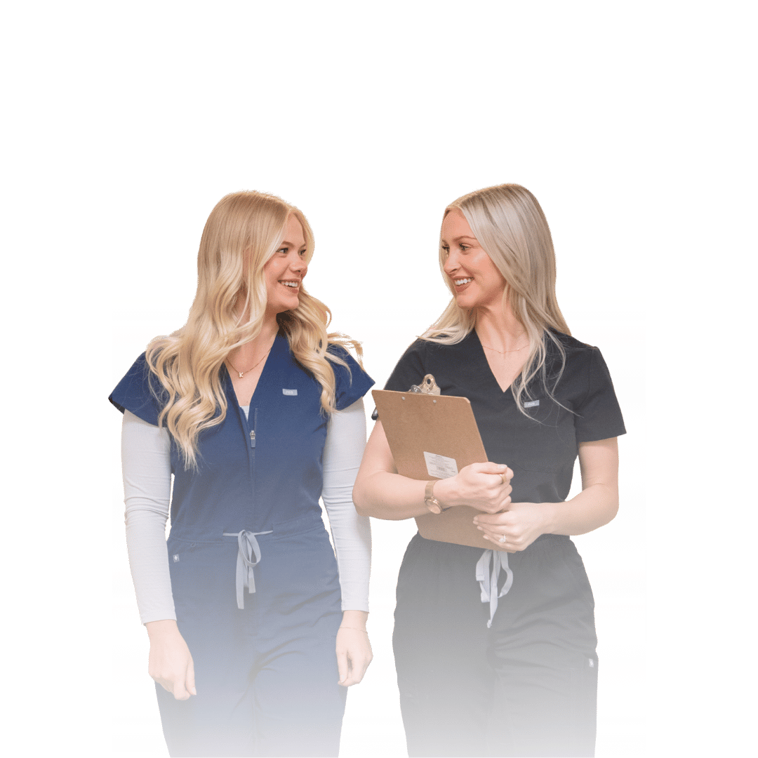 two nurses smiling and walking together with one holding a clipboard